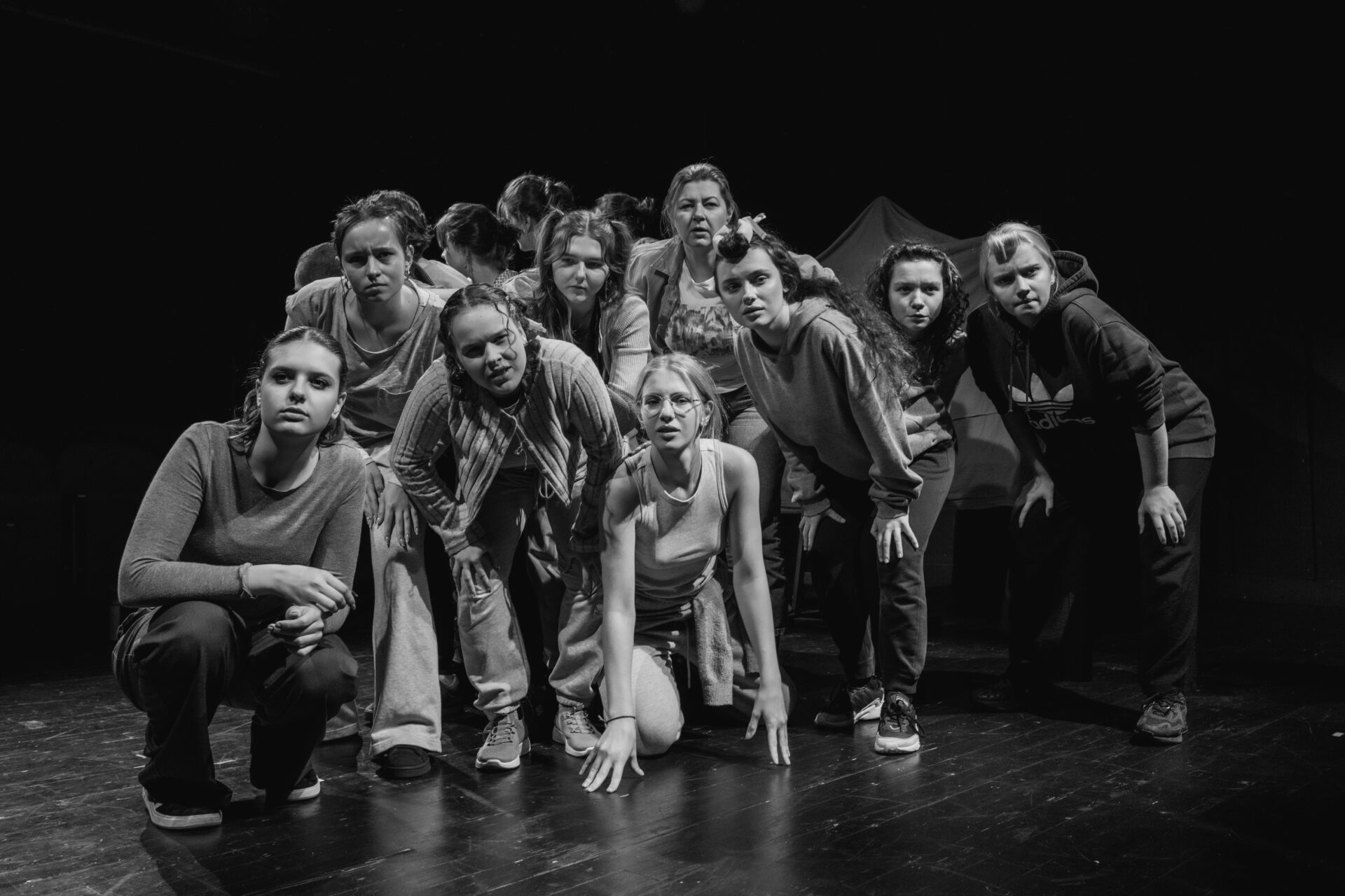 Grupa ludzi, w różnych pozycjach, patrzą w jednym kierunku.