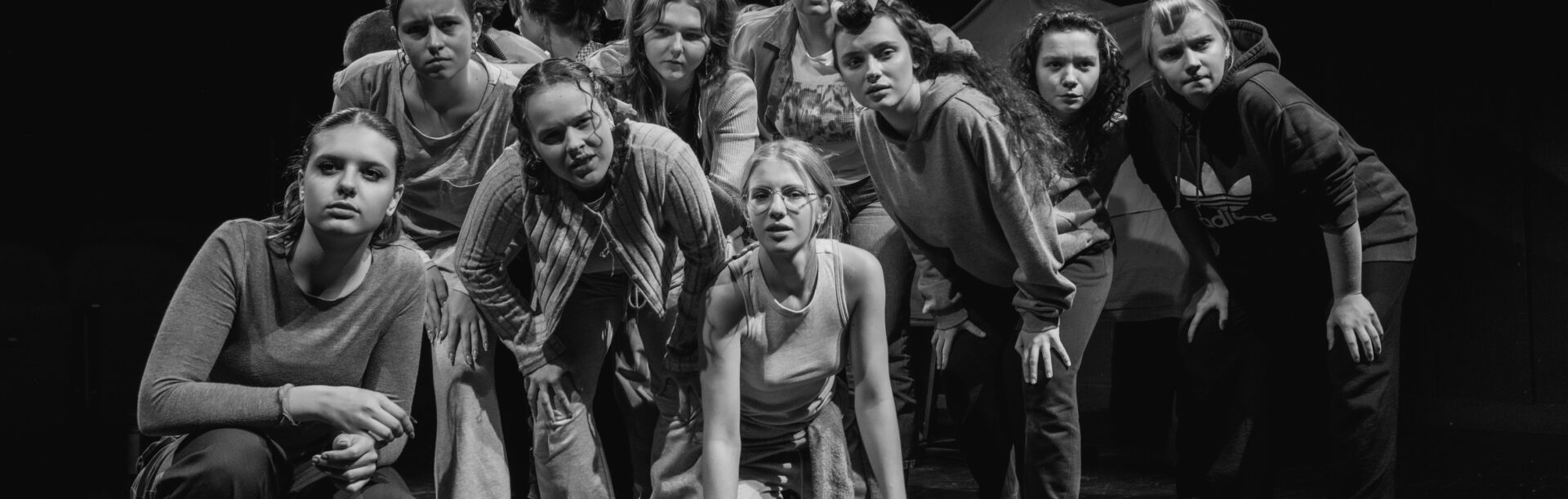 Grupa ludzi, w różnych pozycjach, patrzą w jednym kierunku.