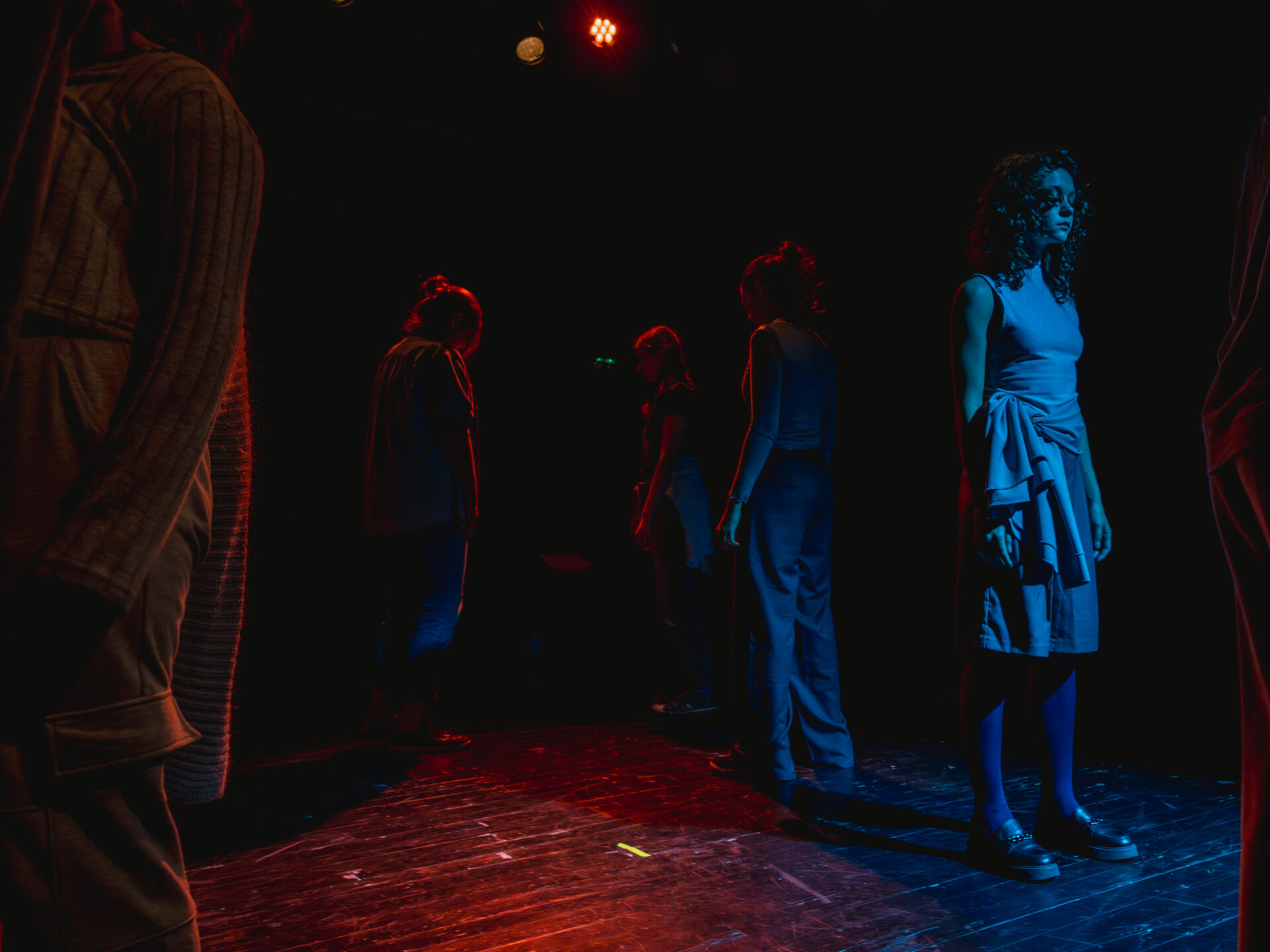 Nastrojowe światło, kilka osób, stoi oddalonych od siebie i patrzy w różnych kierunkach.