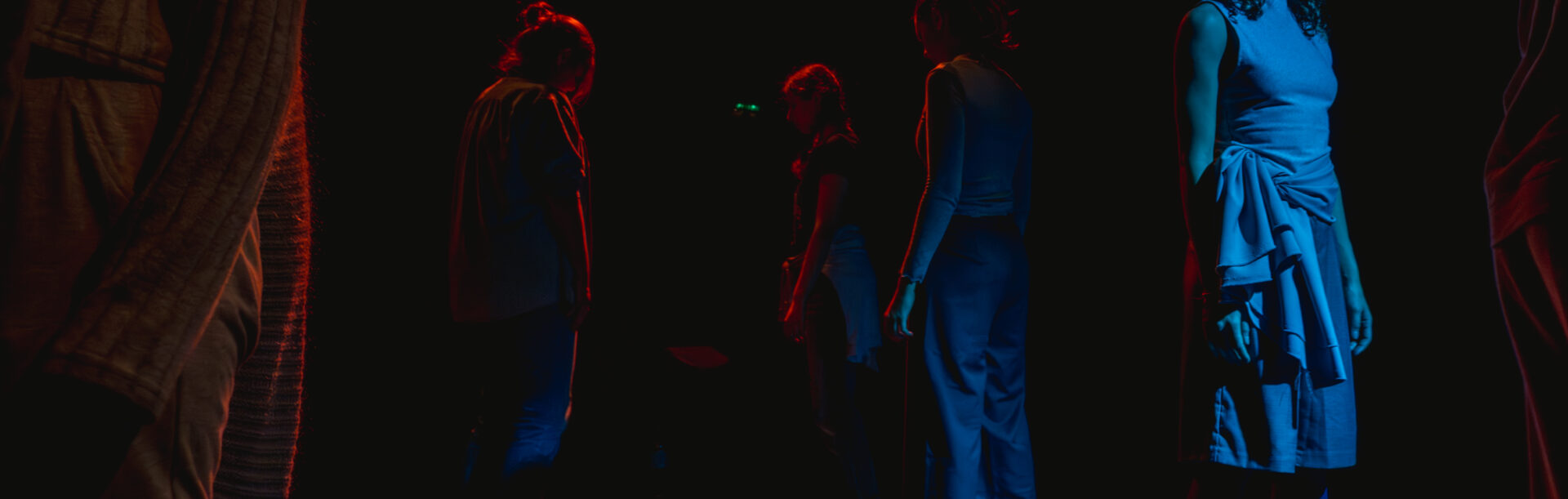 Nastrojowe światło, kilka osób, stoi oddalonych od siebie i patrzy w różnych kierunkach.